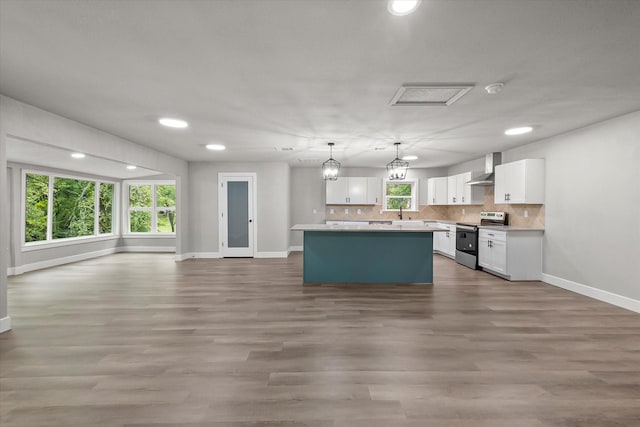 kitchen with electric stove, wall chimney exhaust hood, white cabinetry, baseboards, and open floor plan