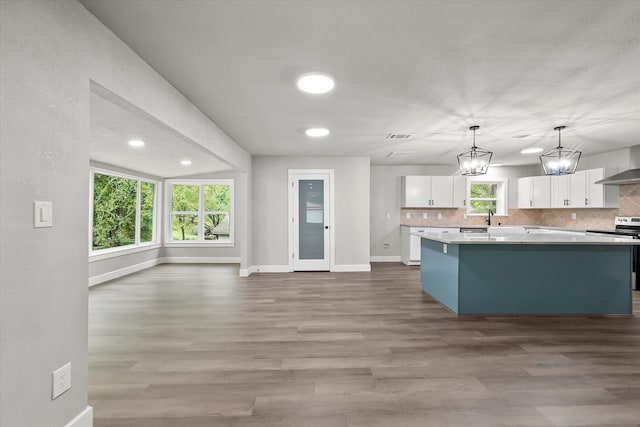 kitchen featuring white cabinets, decorative light fixtures, a wealth of natural light, and stainless steel electric range