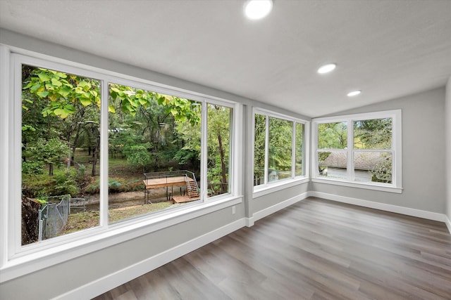 unfurnished sunroom featuring wood finished floors, recessed lighting, vaulted ceiling, and baseboards