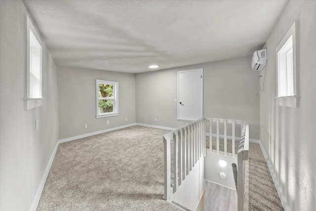 carpeted empty room featuring an AC wall unit