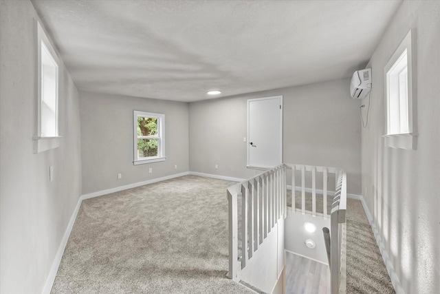 spare room with a wall mounted air conditioner, baseboards, and carpet floors