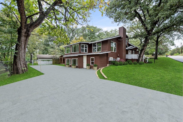 view of front of house featuring an outbuilding, a front lawn, a chimney, and fence