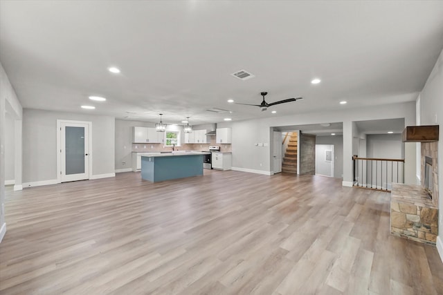 unfurnished living room featuring baseboards, visible vents, stairway, and recessed lighting