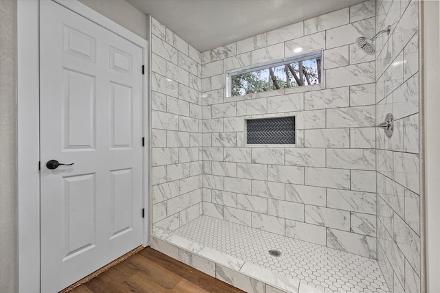 full bathroom featuring tiled shower and wood finished floors