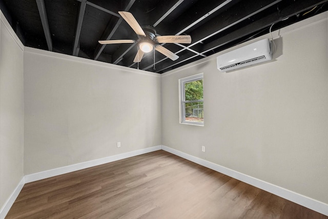 empty room with wood finished floors, ceiling fan, a wall mounted AC, and baseboards