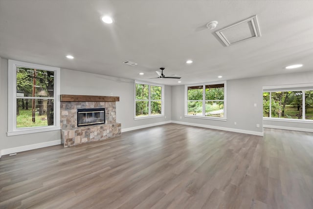 unfurnished living room featuring a stone fireplace, light hardwood / wood-style floors, and a wealth of natural light