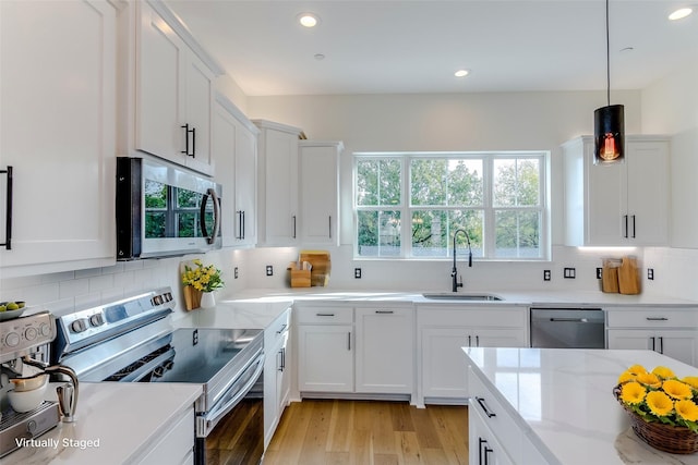 kitchen featuring light wood-style flooring, appliances with stainless steel finishes, white cabinets, and a sink