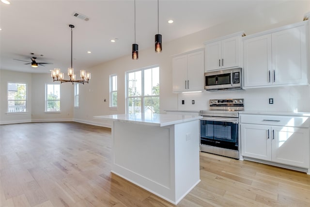 kitchen featuring light wood-style floors, appliances with stainless steel finishes, decorative backsplash, and a center island