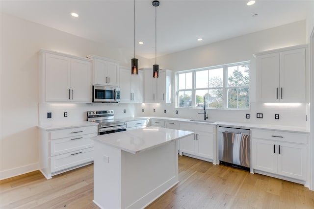 kitchen with white cabinets, appliances with stainless steel finishes, a sink, light wood-type flooring, and backsplash