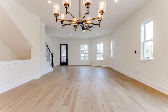 unfurnished living room featuring a wealth of natural light, a notable chandelier, and light wood-style flooring