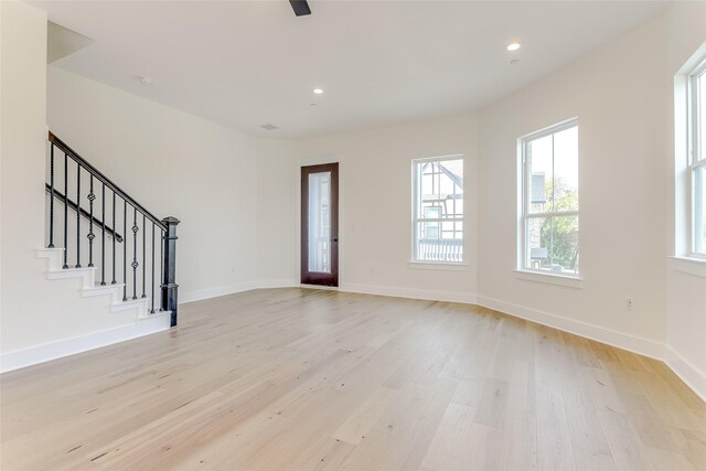 interior space with light wood-style floors, stairway, and baseboards