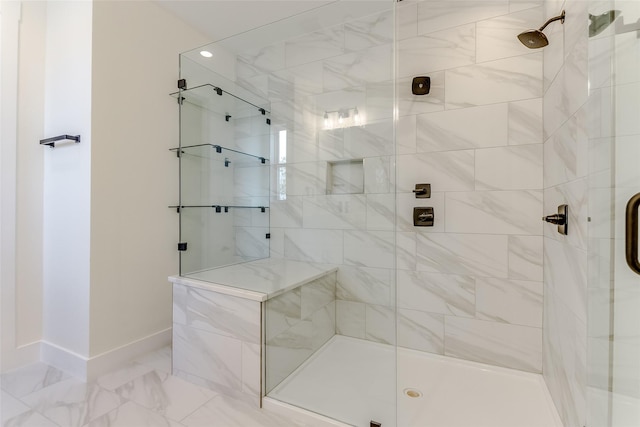 full bath with marble finish floor, a stall shower, and baseboards