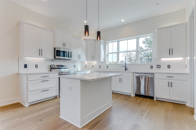 kitchen featuring stainless steel appliances, white cabinetry, light wood-style floors, and tasteful backsplash