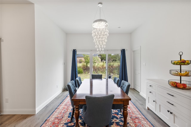 dining space with light hardwood / wood-style flooring and a chandelier