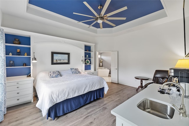 bedroom featuring sink, light hardwood / wood-style floors, a raised ceiling, and ceiling fan