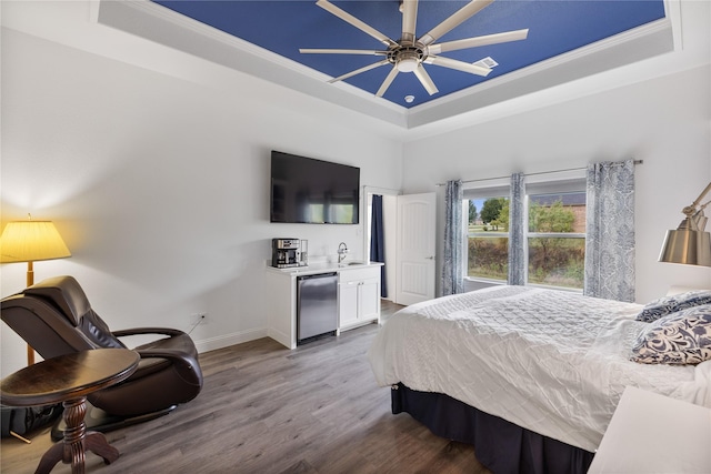 bedroom with a tray ceiling, fridge, and ceiling fan