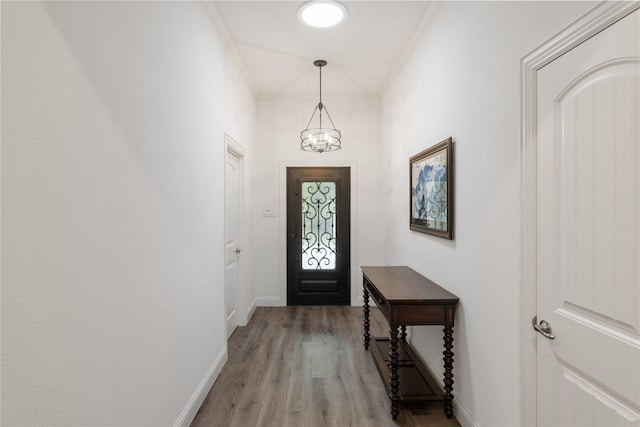 entryway with ornamental molding, light hardwood / wood-style floors, and a chandelier