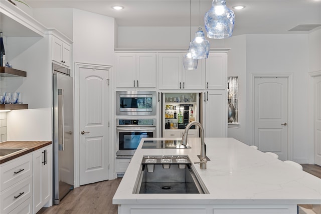 kitchen featuring appliances with stainless steel finishes, a kitchen island with sink, and white cabinets