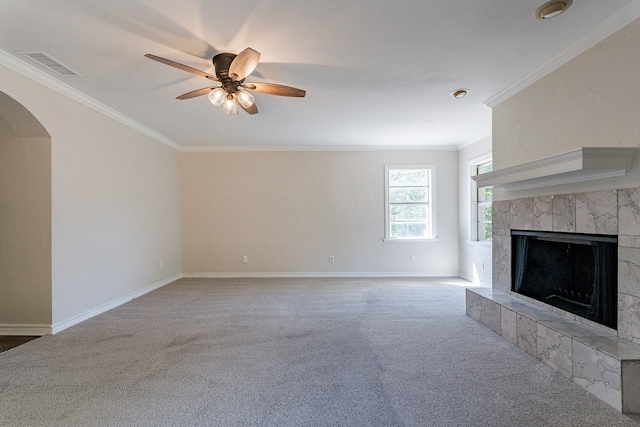 unfurnished living room with a tile fireplace, carpet flooring, ornamental molding, and ceiling fan