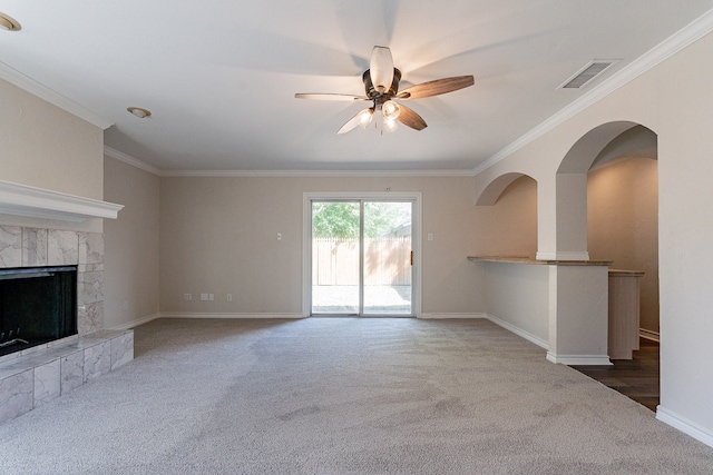 unfurnished living room with ceiling fan, dark colored carpet, a tiled fireplace, and ornamental molding