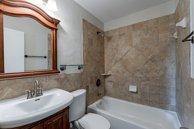 full bathroom featuring tile walls, tasteful backsplash, vanity, tiled shower / bath, and toilet