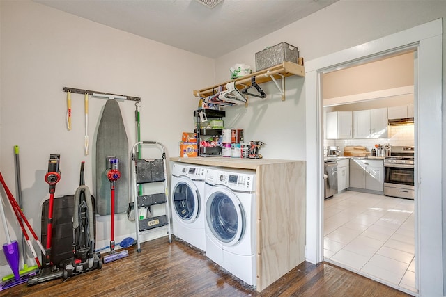 clothes washing area with hardwood / wood-style floors and washer and dryer