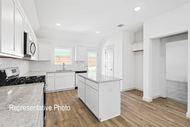 kitchen with white cabinetry, sink, stainless steel appliances, light stone counters, and wood-type flooring