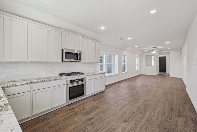 kitchen with white cabinetry, backsplash, light stone counters, stainless steel appliances, and dark wood-type flooring