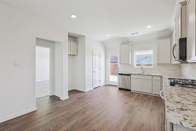 kitchen featuring sink, appliances with stainless steel finishes, dark hardwood / wood-style floors, light stone counters, and tasteful backsplash