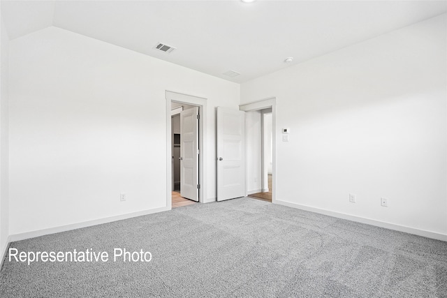 carpeted spare room featuring vaulted ceiling