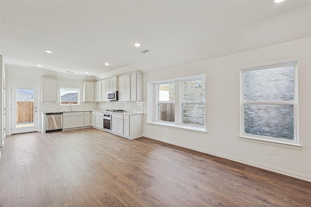 kitchen with appliances with stainless steel finishes, a healthy amount of sunlight, white cabinets, and decorative backsplash