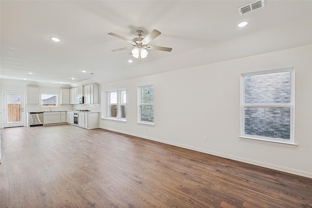 unfurnished living room featuring wood-type flooring, sink, and ceiling fan