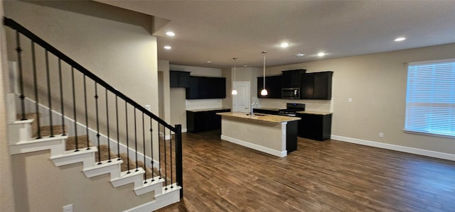 kitchen with dark hardwood / wood-style floors, sink, black electric range oven, hanging light fixtures, and a center island with sink