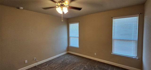 spare room featuring ceiling fan, a healthy amount of sunlight, and dark carpet