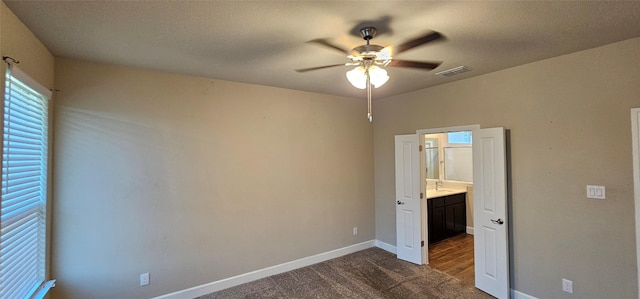 unfurnished bedroom with ceiling fan, sink, and dark carpet