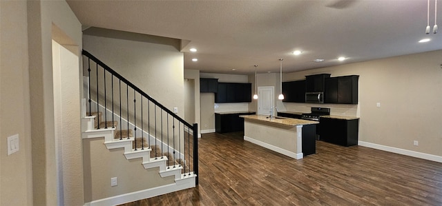 kitchen featuring an island with sink, sink, backsplash, dark hardwood / wood-style flooring, and light stone counters