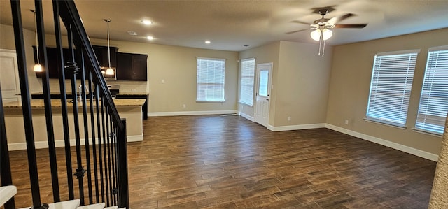 unfurnished living room featuring ceiling fan, dark hardwood / wood-style floors, and a wealth of natural light