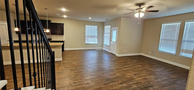 unfurnished living room with dark hardwood / wood-style flooring and ceiling fan