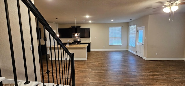 kitchen with sink, light stone counters, appliances with stainless steel finishes, dark hardwood / wood-style flooring, and an island with sink