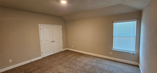 unfurnished bedroom featuring a closet, lofted ceiling, carpet floors, and multiple windows