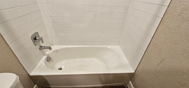 bathroom featuring tiled shower / bath and toilet