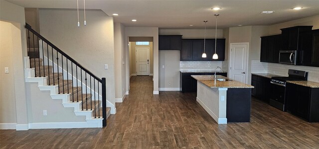 kitchen with a center island with sink, electric range, dark hardwood / wood-style floors, light stone countertops, and backsplash