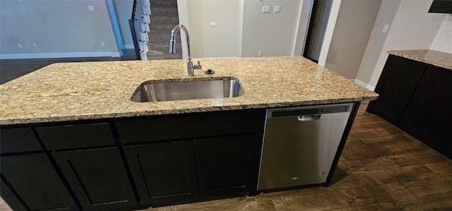 kitchen featuring dark wood-type flooring, stainless steel dishwasher, a kitchen island with sink, and sink