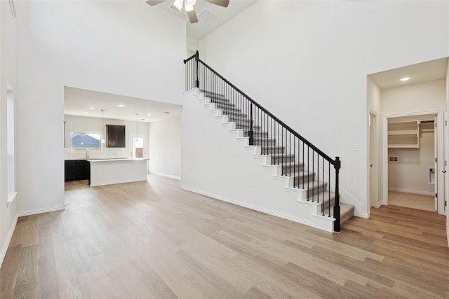 3913 Sky Dr, Sherman, TX 75090 - unfurnished living room featuring a ceiling fan, stairs, light wood-type flooring, a sink, and a towering ceiling