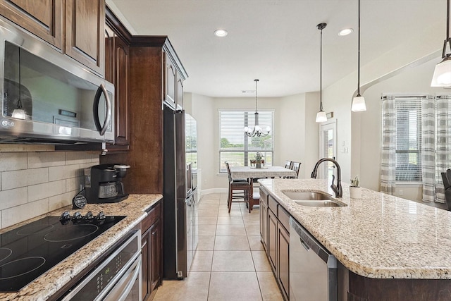 kitchen with a kitchen island with sink, stainless steel appliances, hanging light fixtures, a notable chandelier, and sink