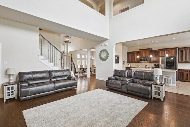 living room featuring a high ceiling, a notable chandelier, and dark wood-type flooring