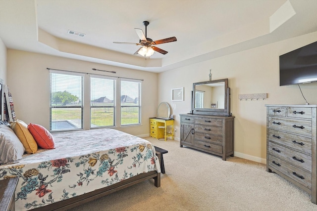 carpeted bedroom featuring ceiling fan and a raised ceiling