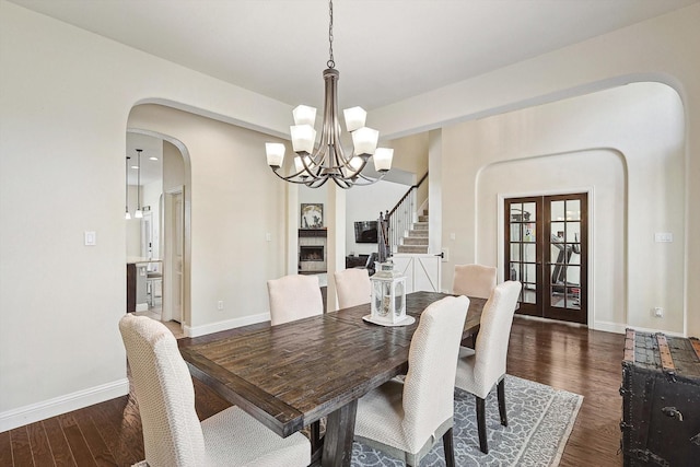 dining room featuring dark wood-type flooring, a notable chandelier, and french doors