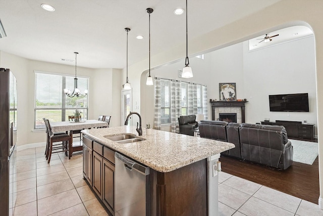 kitchen with sink, stainless steel dishwasher, light tile patterned floors, and hanging light fixtures