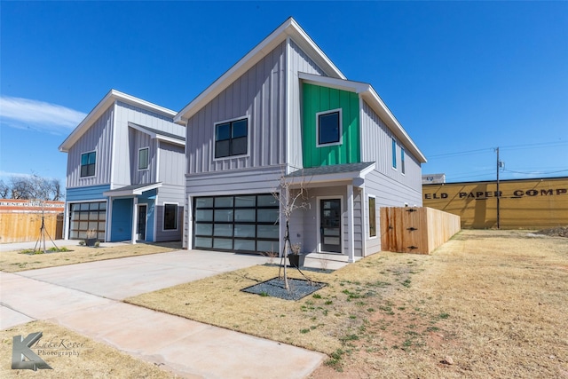 view of front of property with driveway, board and batten siding, an attached garage, and fence